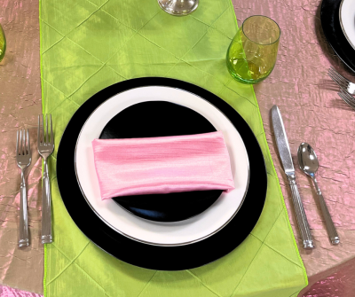 Elphaba and Glinda Wicked themed place setting design with black and white plates, emerald green stemless glass, pink Crush tablecloth and runner